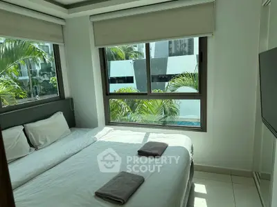 Bright bedroom with large windows and pool view, featuring twin beds and modern decor.