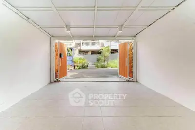 Spacious garage with open doors leading to a driveway and garden view.