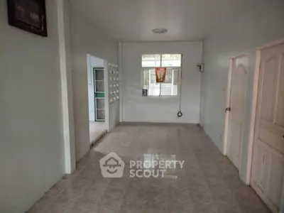 Spacious empty room with tiled flooring and natural light, ideal for customization.