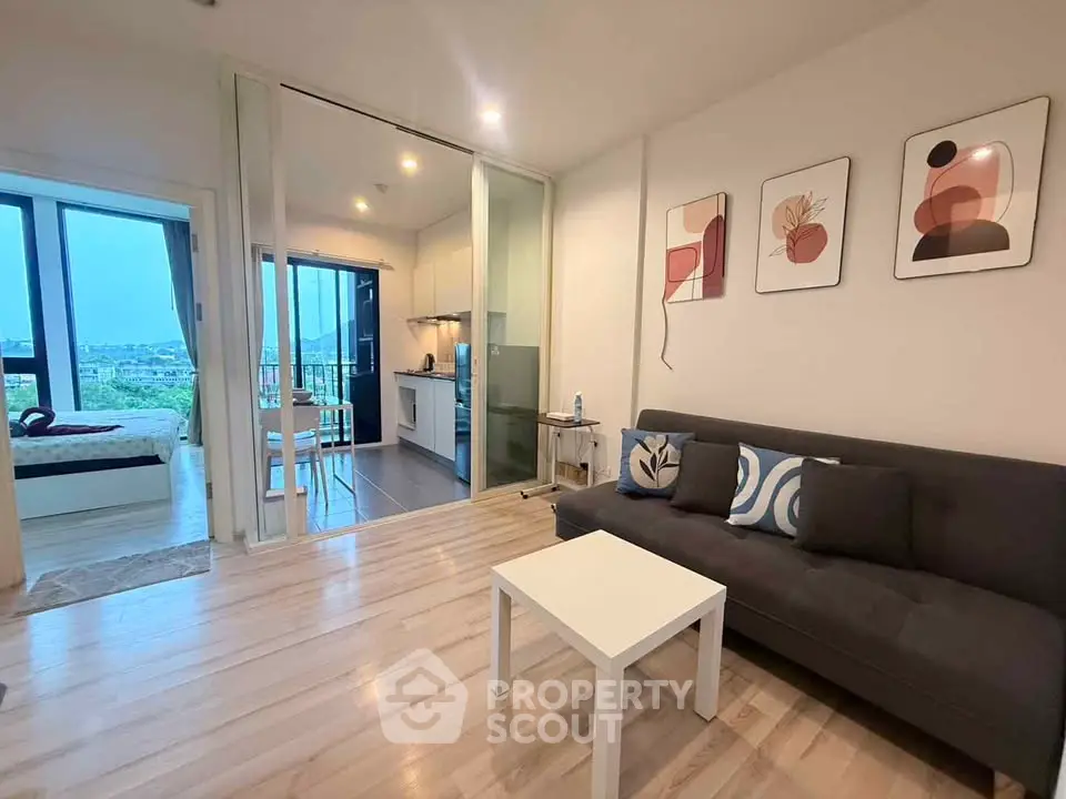 Modern living room with open layout and stylish decor, featuring a cozy sofa and adjacent kitchen area.