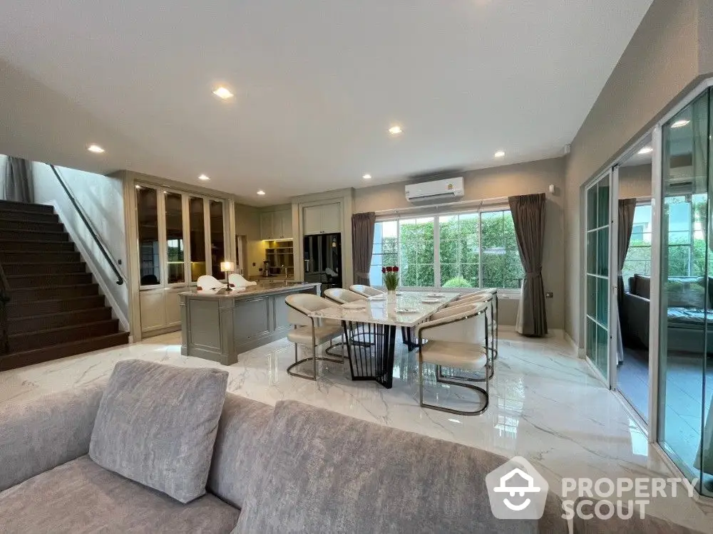 Spacious living area seamlessly connects to an open layout kitchen, featuring modern appliances, ample lighting, and access to outdoor views, ideal for entertaining and relaxation.