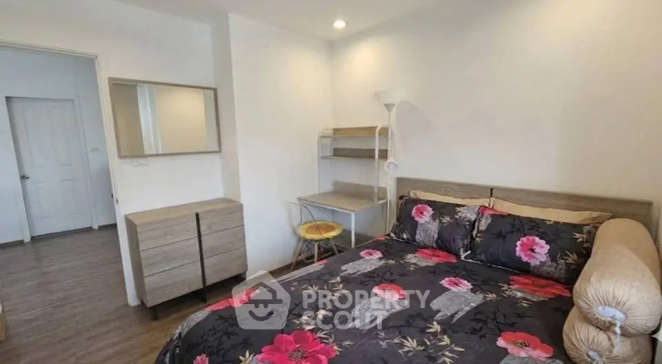 Cozy bedroom with floral bedding, modern furniture, and a small workspace in a bright apartment.