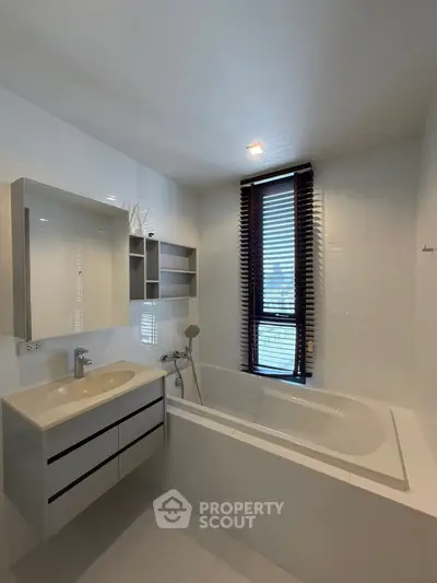 Modern bathroom with sleek design featuring a bathtub and large window with blinds.