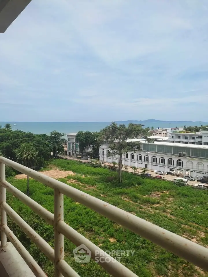 Stunning ocean view from a balcony overlooking lush greenery and urban landscape.