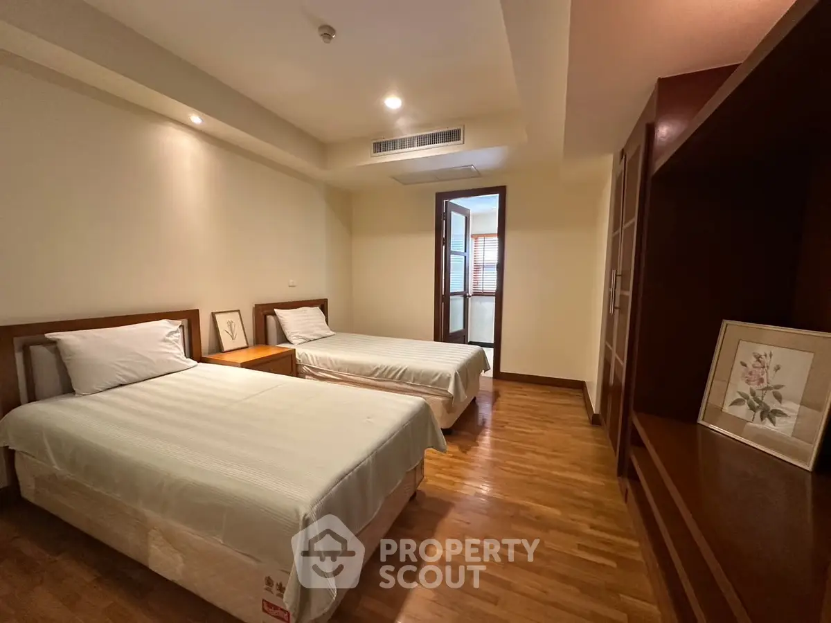 Spacious bedroom with twin beds and wooden flooring in modern apartment