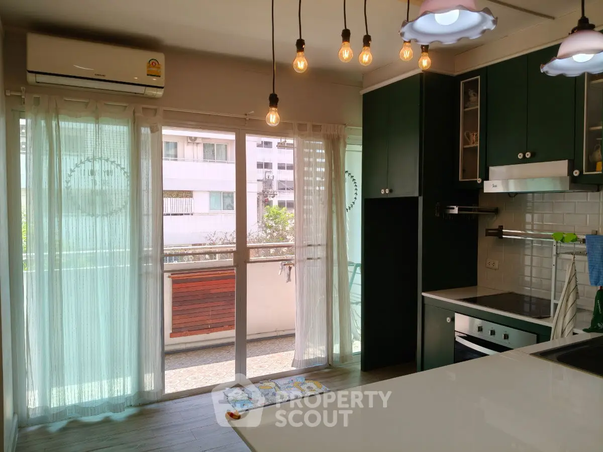 Modern kitchen with open layout and balcony access, featuring stylish lighting and sleek cabinetry.
