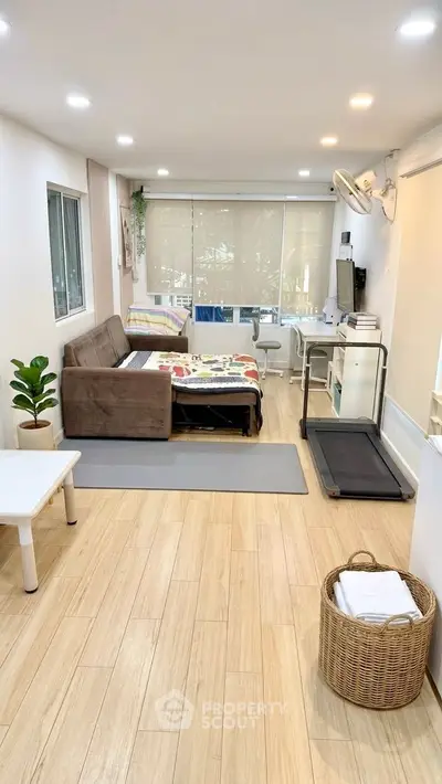 Spacious living room with treadmill and cozy seating area, perfect for relaxation and fitness.