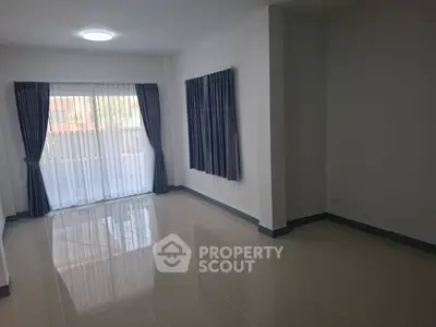 Spacious empty room with large window and blue curtains, perfect for customization.