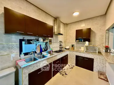 Modern kitchen with dark cabinets and open layout, featuring stainless steel appliances and granite countertops.