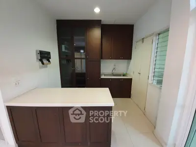 Modern kitchen with dark wood cabinets and white countertops in a cozy apartment.