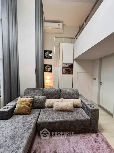 Modern loft apartment with stylish gray sofa and high ceilings, perfect for urban living.