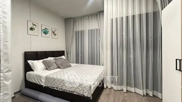 Modern bedroom with elegant decor and floor-to-ceiling curtains in a stylish apartment.