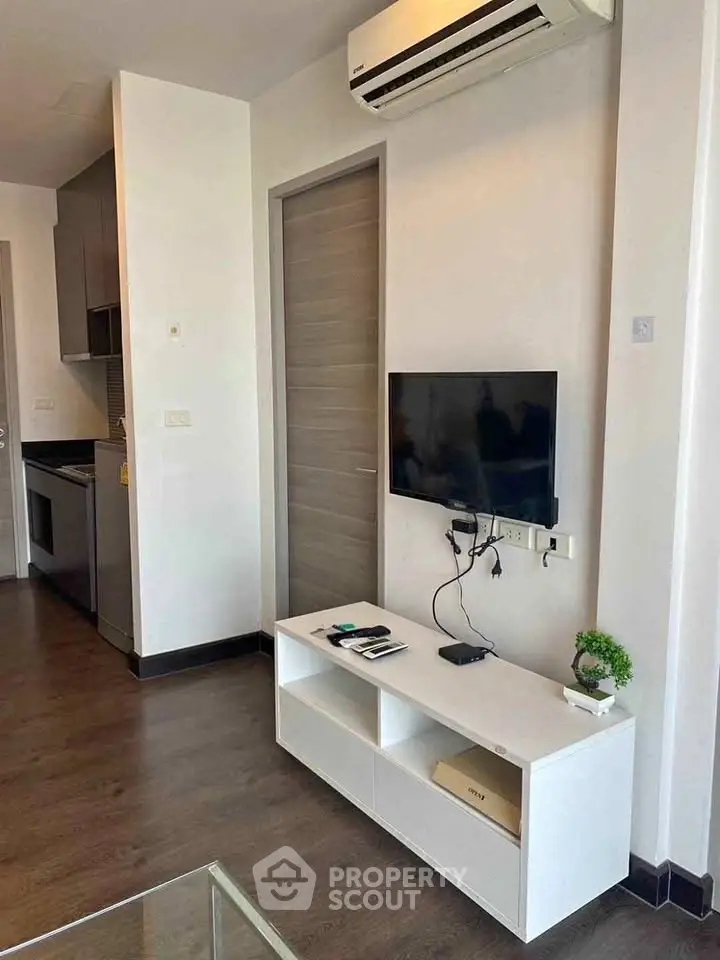 Modern living room with sleek TV setup and air conditioning in a stylish apartment.