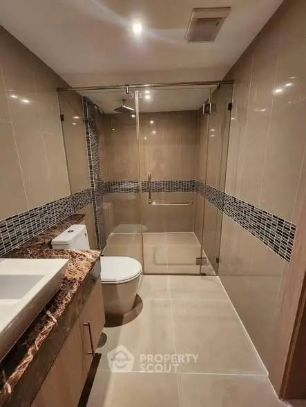 Modern bathroom with glass shower enclosure and elegant tile design.