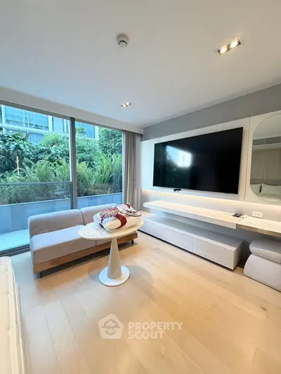 Modern living room with large TV and garden view, featuring sleek furniture and natural light.