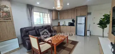 Modern living room with open kitchen, featuring sleek wooden cabinets and comfortable seating.