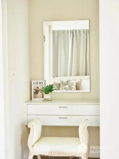 Elegant bedroom vanity with mirror and plush seating in a bright, cozy space.