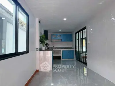 Modern kitchen with blue cabinets and sleek tile flooring in a bright, open layout.