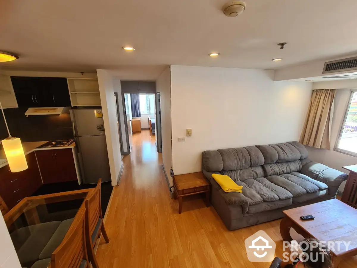 Spacious living room seamlessly connected to a modern kitchen with stainless steel appliances, ample cabinetry, and a cozy dining area, all bathed in natural light.