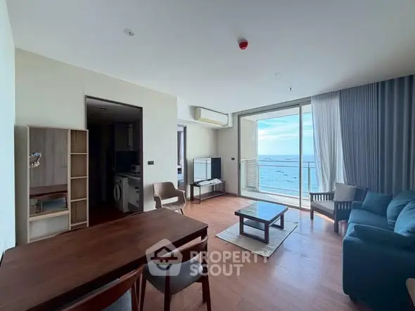 Spacious living room with ocean view and modern furnishings in a high-rise apartment.