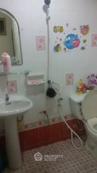 Charming bathroom with playful wall decals and essential fixtures, perfect for a cozy home.