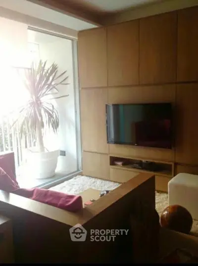 Modern living room with sleek wooden paneling and large potted plant near balcony.