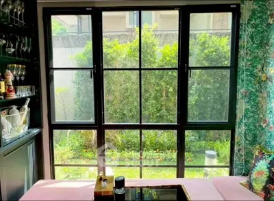 Charming living room with large windows overlooking lush garden, perfect for relaxation and entertaining.