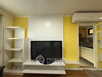 Modern living room with TV and air conditioning, adjacent to a stylish kitchen.