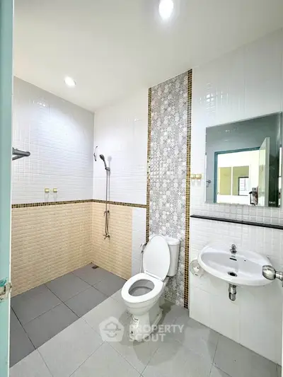 Modern bathroom with sleek design, featuring a shower and toilet in a bright, tiled space.