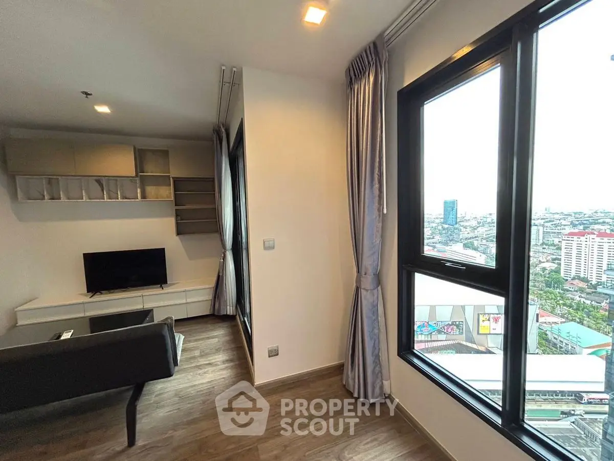 Modern living room with large windows offering city view and stylish furnishings.