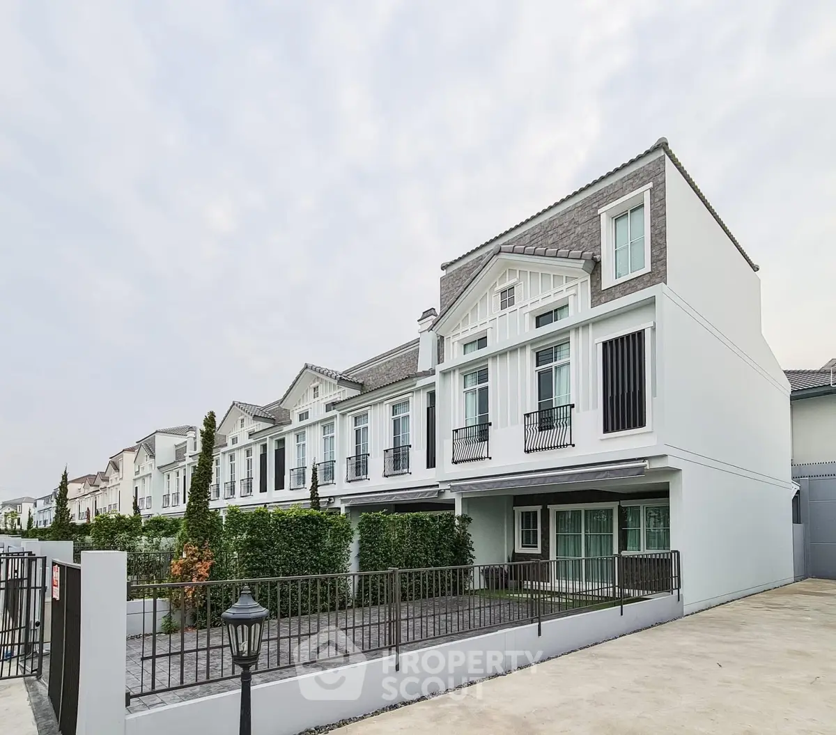 Elegant row of modern townhouses with spacious driveways and lush greenery.