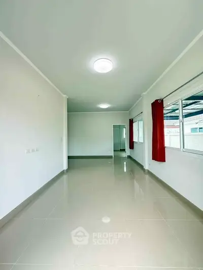 Spacious empty room with glossy tiled floor and large windows, perfect for customization.