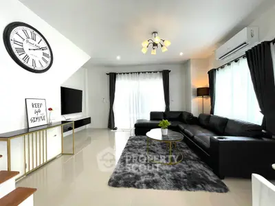 Modern living room with sleek black furniture, stylish decor, and ample natural light for a cozy ambiance.