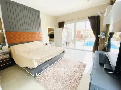 Luxurious bedroom with pool view, modern decor, and ample natural light in a stunning real estate property.