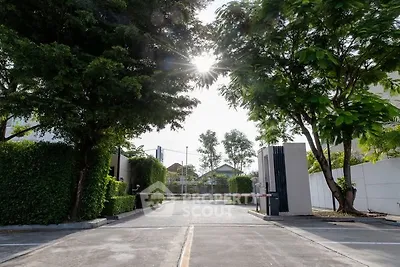 Gated entrance to a serene residential community with lush greenery and modern security features.