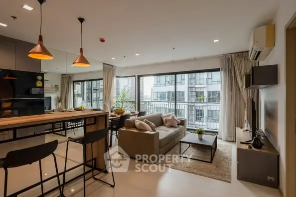 Modern open-plan living room with stylish kitchen and large windows in a high-rise apartment.