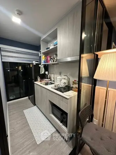 Modern compact kitchen with sleek cabinetry and appliances in a cozy apartment setting.