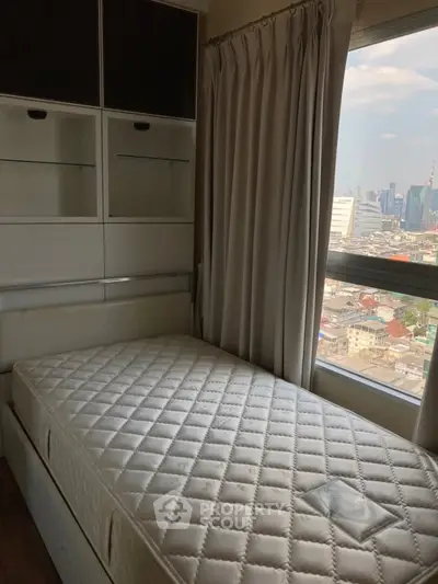 Cozy bedroom with city view, featuring a single bed and built-in storage, perfect for urban living.
