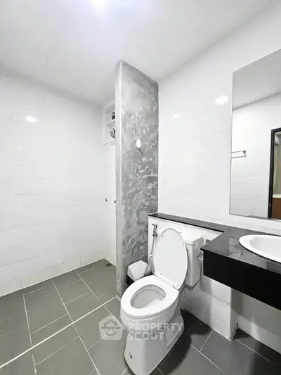 Modern bathroom with sleek design, featuring a toilet and stylish sink area.