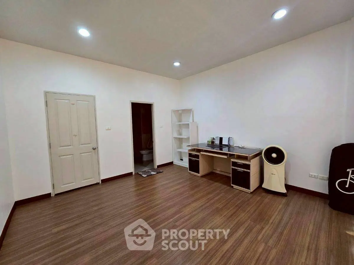 Spacious room with wooden flooring and modern desk setup