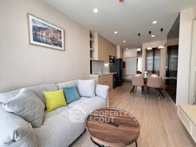 Modern living room with cozy sofa, stylish dining area, and sleek kitchen in open layout apartment.