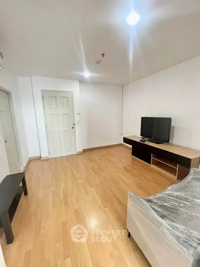 Spacious living room with wooden flooring and modern TV setup