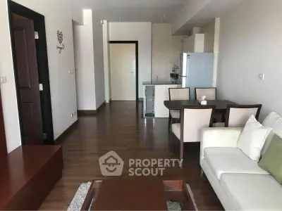 Spacious living room with modern furniture and open layout, featuring a dining area and sleek kitchen appliances.