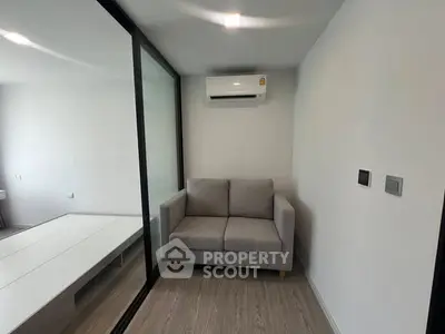 Modern minimalist living room with sleek glass partition and cozy gray sofa.