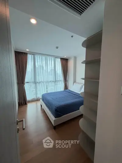 Modern bedroom with large window and wooden flooring in a high-rise apartment.