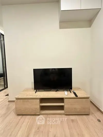 Modern living room with sleek TV stand and flat-screen TV on wooden flooring.