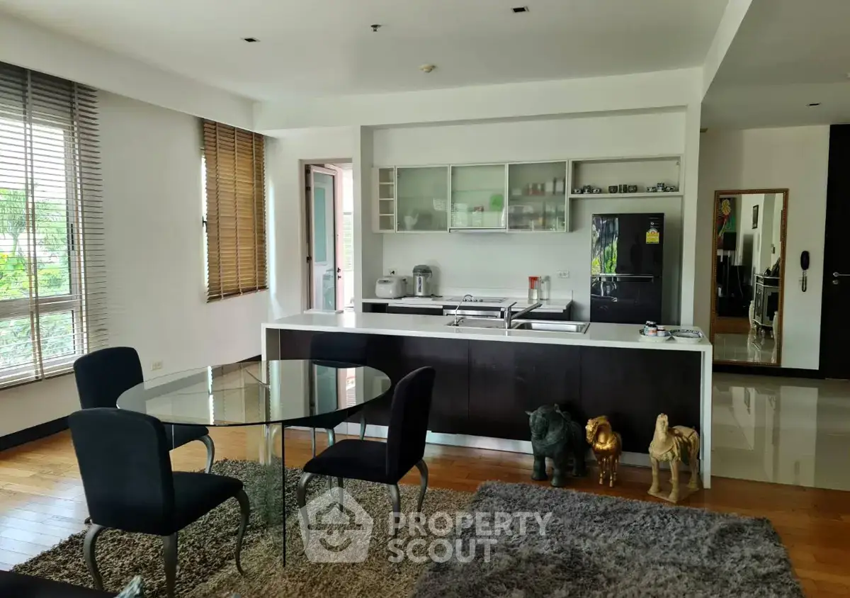 Modern open-layout kitchen and dining area with stylish decor and large windows.