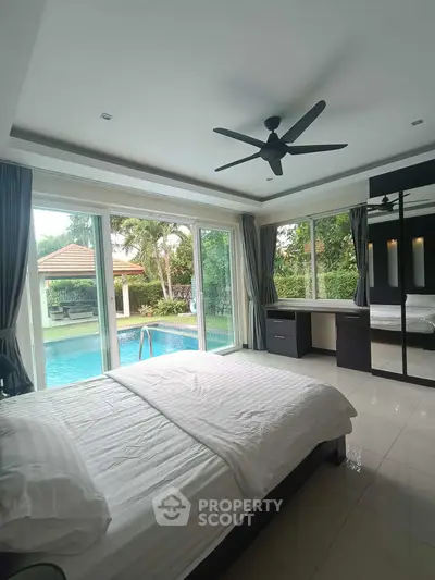 Luxurious bedroom with pool view and modern furnishings in a tropical setting.