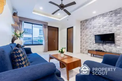 Modern living room with blue sofas, wooden coffee table, and wall-mounted TV