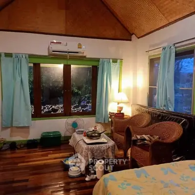 Cozy rustic cabin-style living room with wooden floors, wicker furniture, and a warm, inviting atmosphere, surrounded by nature.